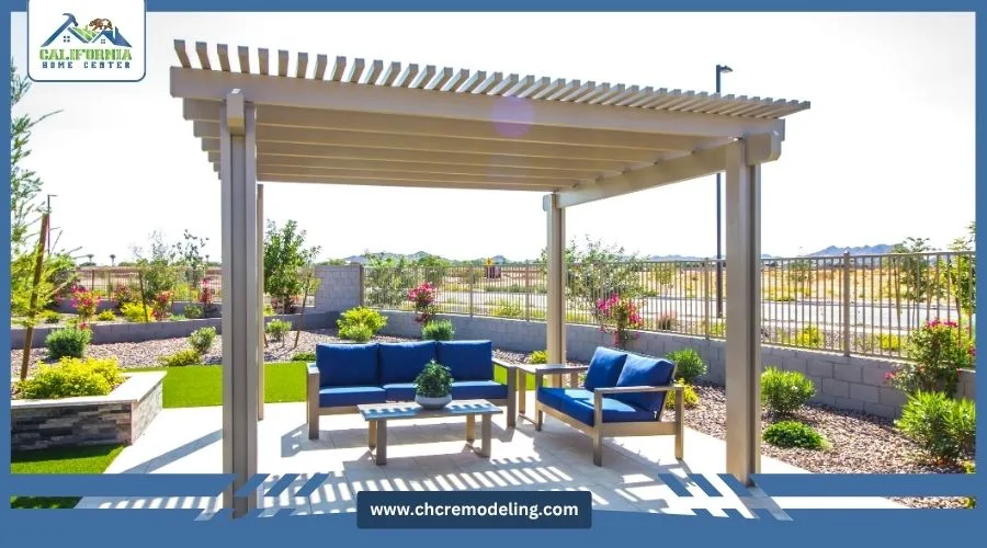 Backyard patio featuring an open-slat louvered pergola structure over blue outdoor sofas and a coffee table by California Home Center.