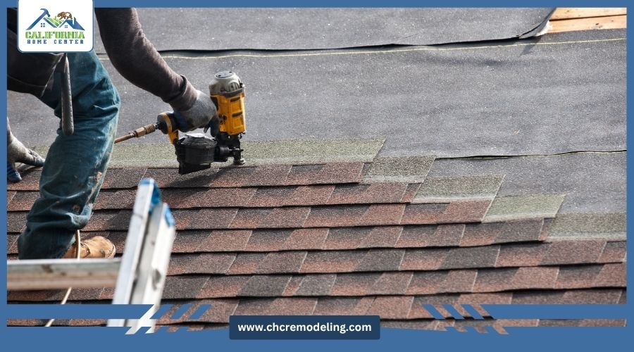 Close-up of a roofer using a pneumatic nail gun to install brown asphalt shingles on a roof, featuring the California Home Center logo.